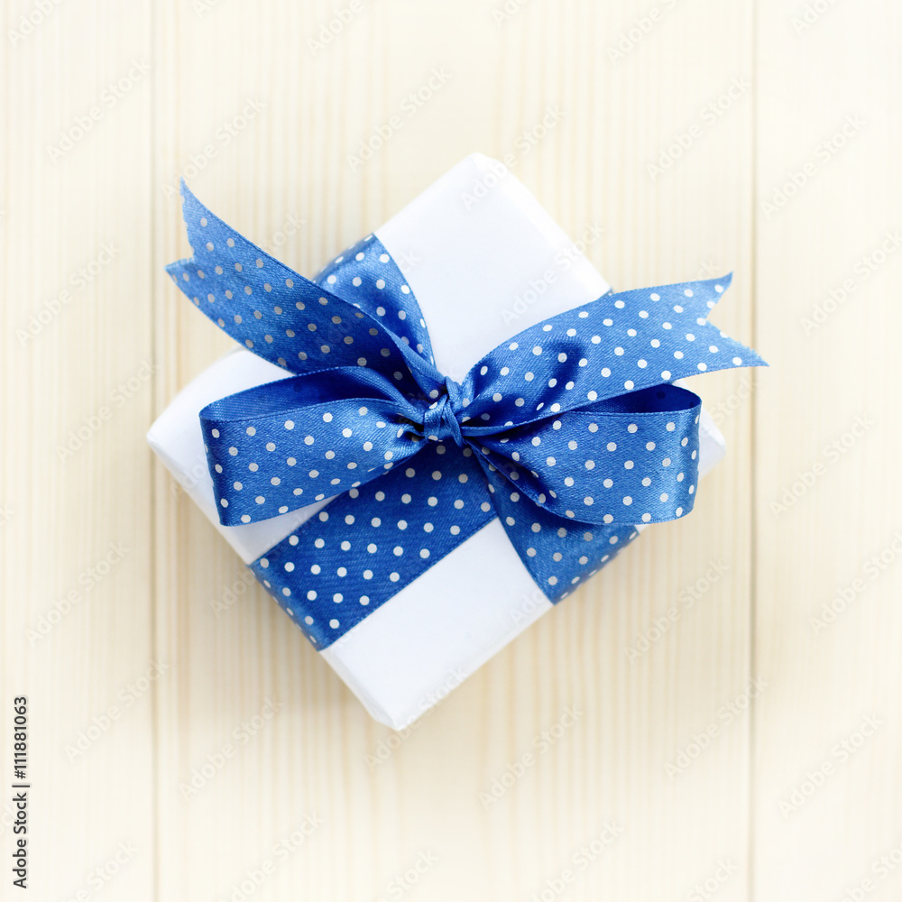 blue bow-knot polka dots for a gift/ idea holiday gift with ribbon on a wooden table top view 