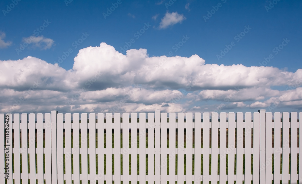 A white fence blocking a blue sky A white fence blocking a blue sky