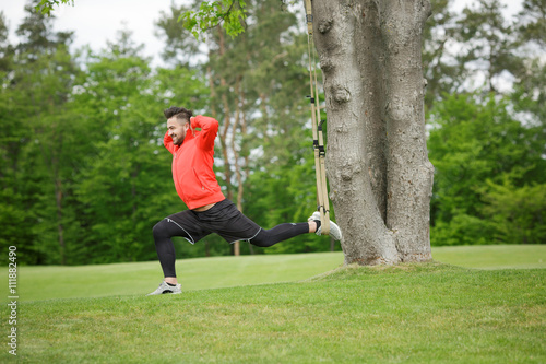 Sport man stretching in park. Young man doing sports exercises. Fitness and sports concepts.