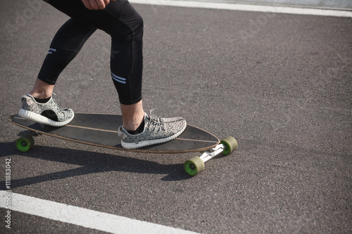 Man riding on longboard on road. Fitness or sport man resting and relaxing outdoors. Action shot of alongboarder skating on urban road.
