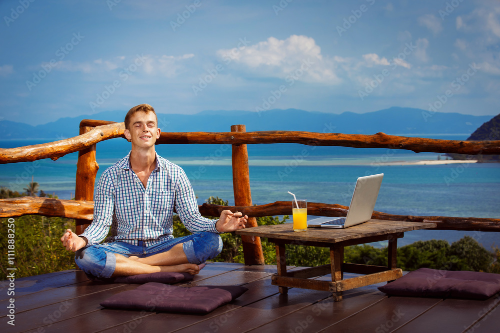 Young man  is sitting with closed eyes in yoga pose