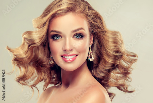 Beautiful girl blonde hair with an elegant hairstyle , hair wave ,curly hairstyle . Jewellery , earrings and bracelet