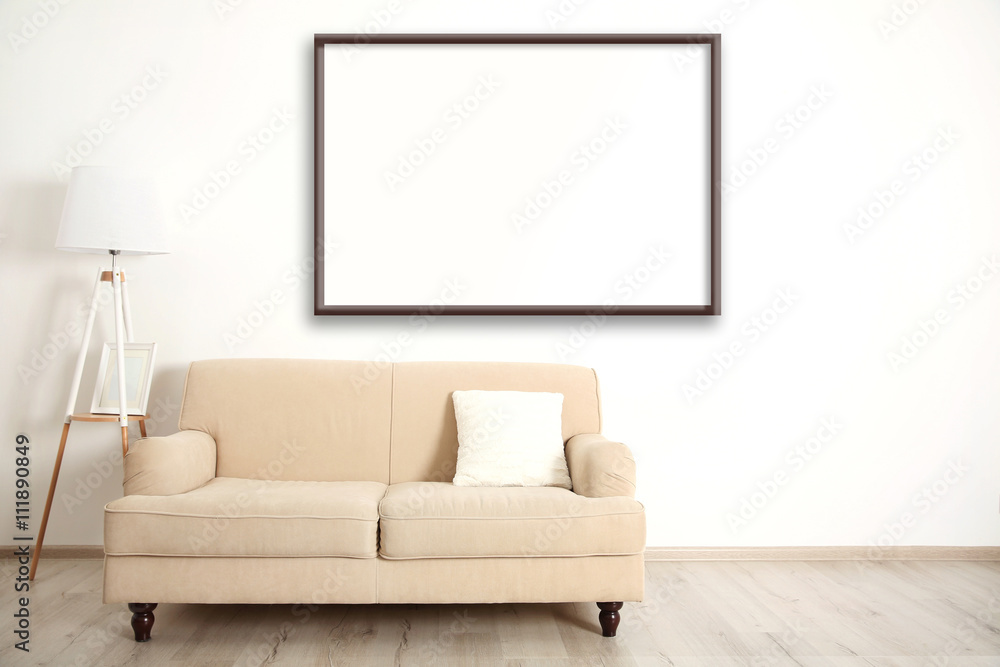 Beige couch with lamp and empty picture frame on wall background Beige couch with lamp and empty picture frame on wall background