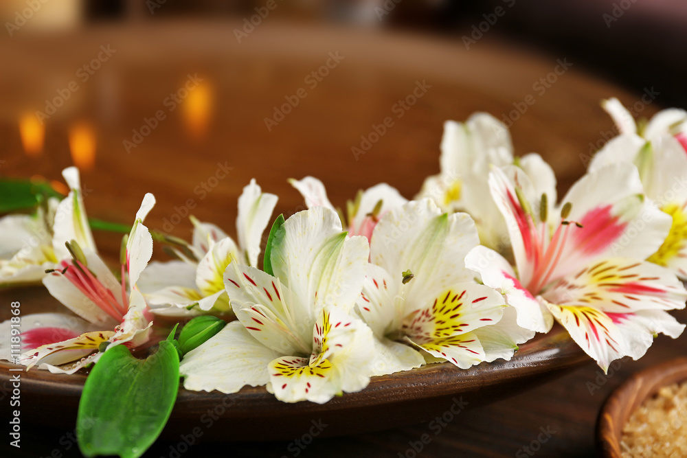 Spa wooden bowl with water and flowers closeup