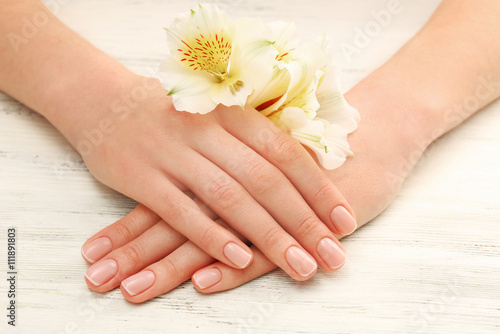 Spa concept. Woman hands with beautiful flowers and nail polish on wooden background  close up