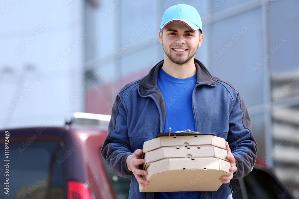 Young man holding pizza outside