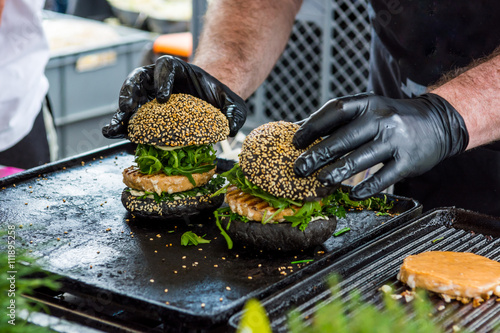 Chef preparing tasty burgers at outdoor stand. photo