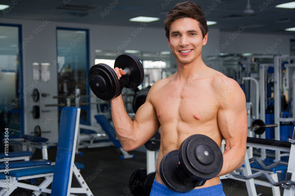 Young smiling athlete lifting weights in the gym Young smiling athlete lifting weights in the gym
