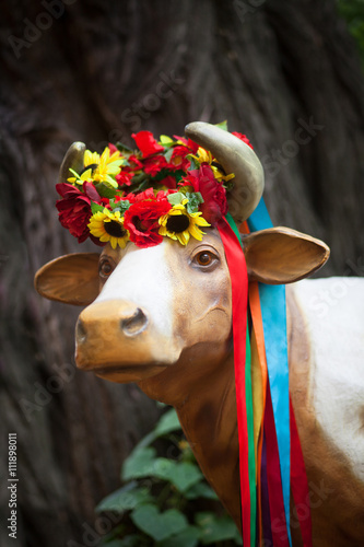 Pretty cow in Ukrainian bright wreath with flowers and ribbons
