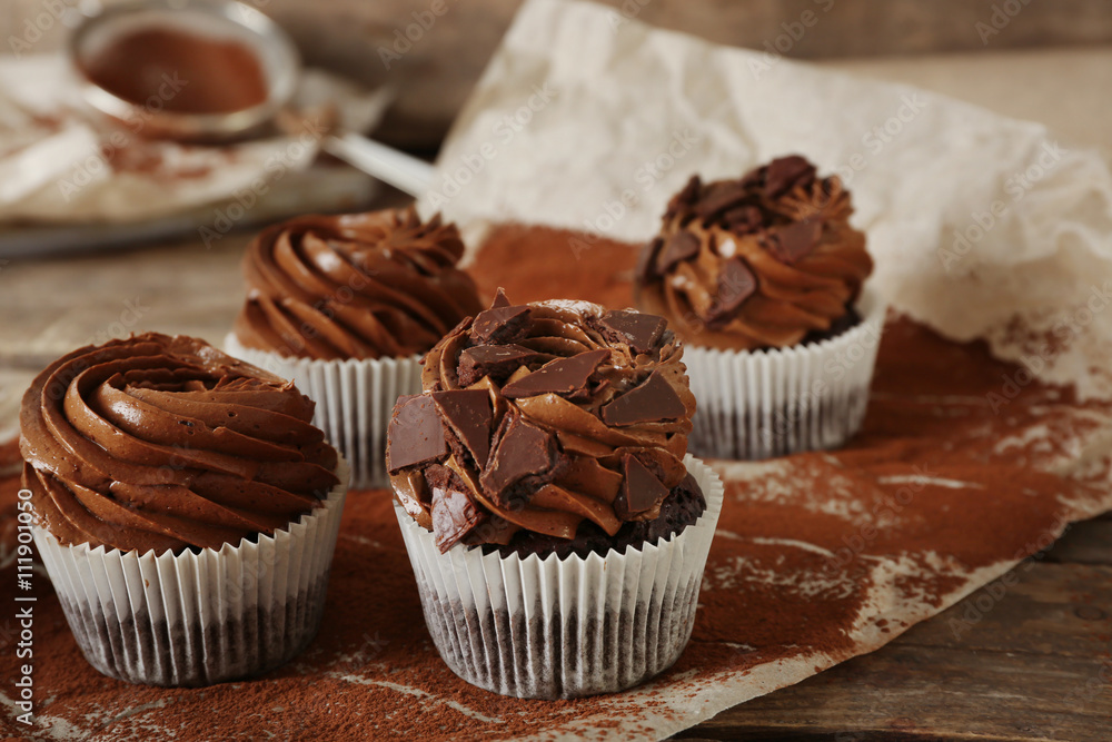 Chocolate cupcakes on baker paper over wooden background Chocolate cupcakes on baker paper over wooden background