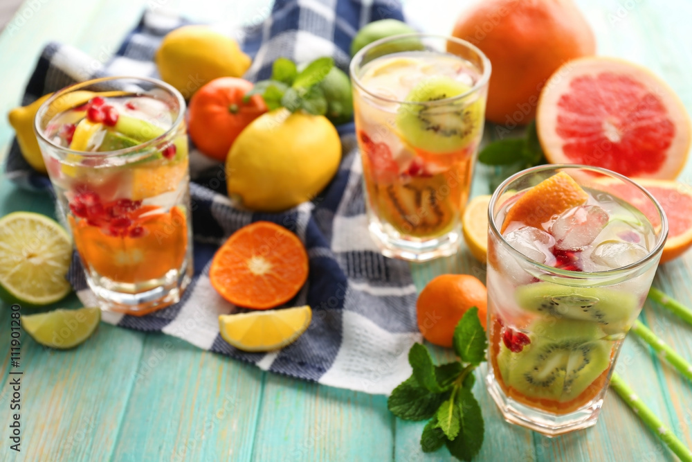 Refreshing cocktails with ice, mint, pomegranate seeds and slices of fruits on blue wooden background Refreshing cocktails with ice, mint, pomegranate seeds and slices of fruits on blue wooden background