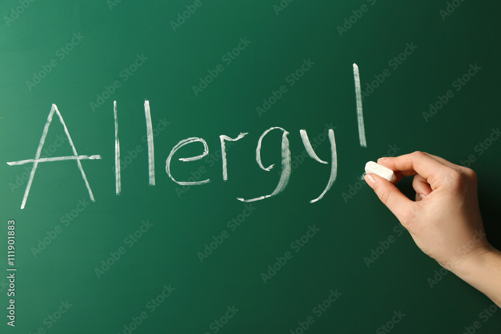 Allergy food concept. Hand with chalk writing on blackboard Allergy food concept. Hand with chalk writing on blackboard