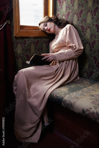 Young woman in beige vintage dress of early 20th century reading © Serg Zastavkin