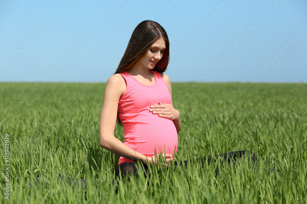 Pregnant woman relaxing in field Pregnant woman relaxing in field