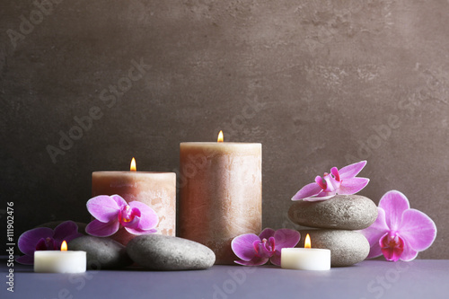 Composition of spa pebbles  flowers and candles on grey background