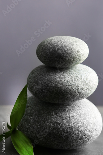 Composition of spa pebbles with bamboo leaf on grey wall background