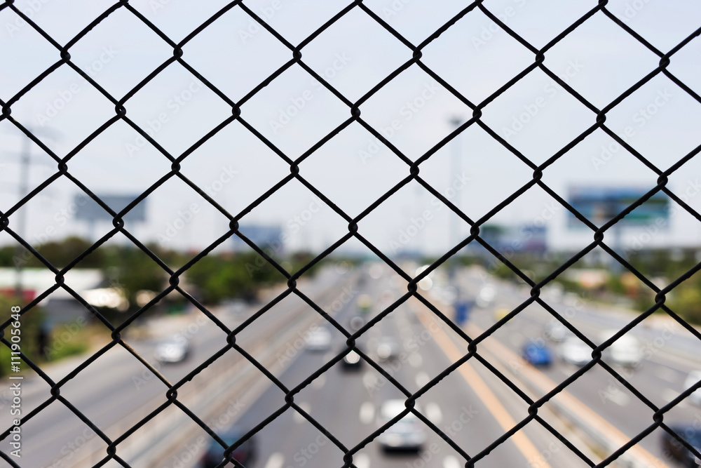 steel wire mesh (mesh fence) with city road highway out focus steel wire mesh (mesh fence) with city road highway out focus