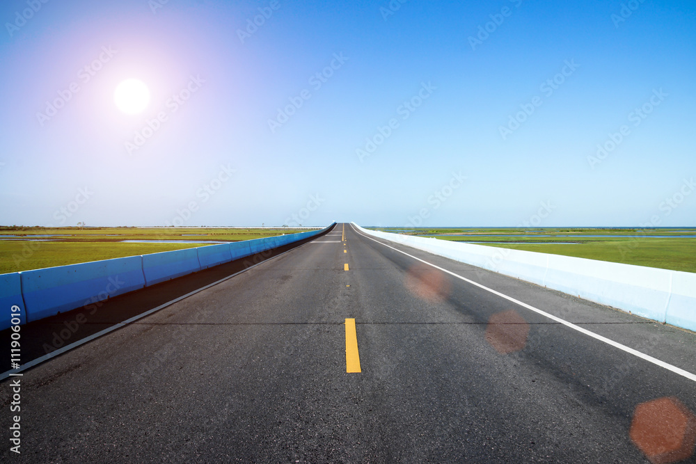 Empty road and the yellow traffic lines with blue sky.
