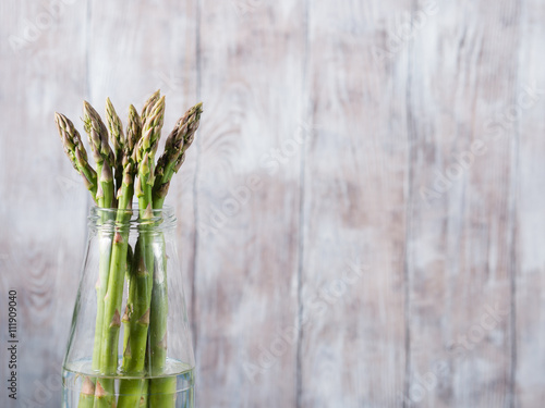 Organic asparagus in a glass bottle on wooden textured background. Copy space