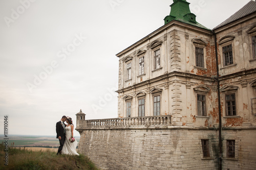 Beautiful romantic wedding couple of newlyweds hugging near old castle  © olegparylyak