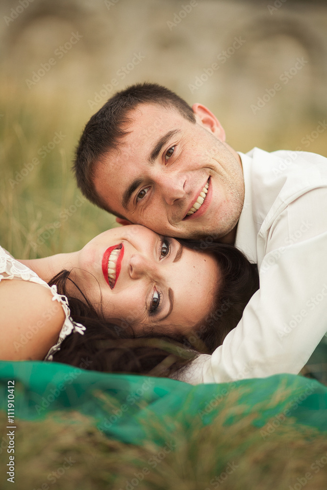 Happy wedding couple lying on green grass at the summer time Happy wedding couple lying on green grass at the summer time