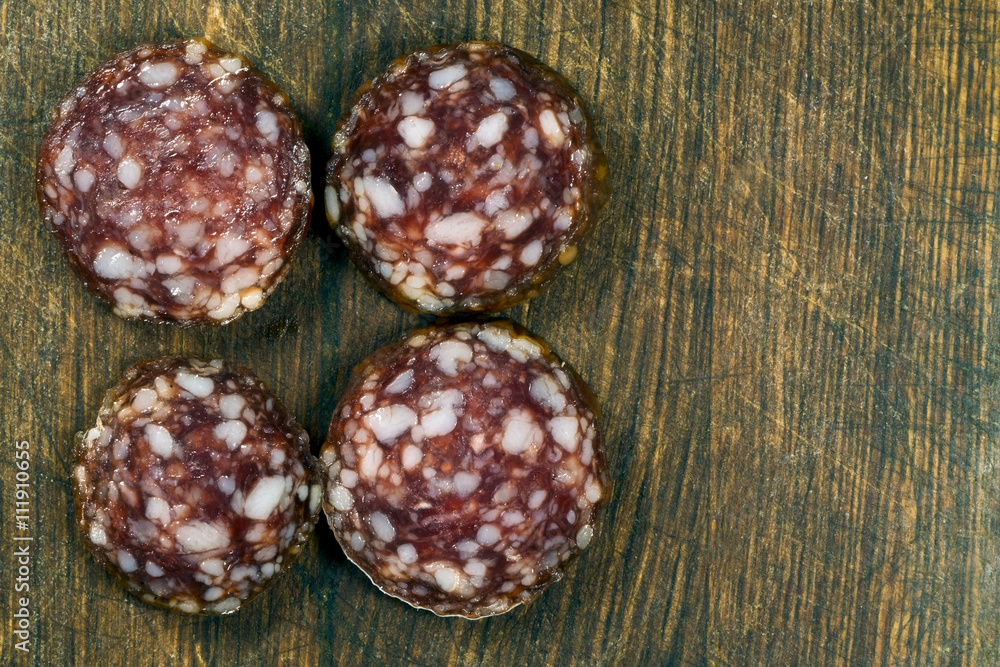 4 pieces of smoked sausage on a wooden board
