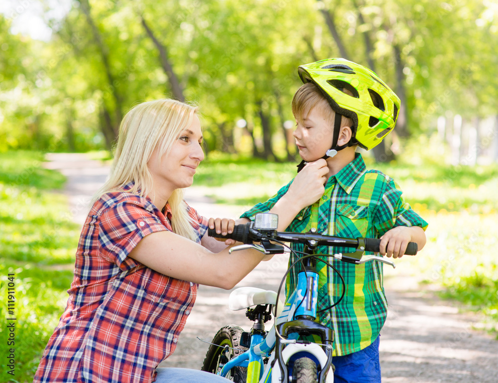 mother taking care of her son, wearing his bicycle helmet mother taking care of her son, wearing his bicycle helmet