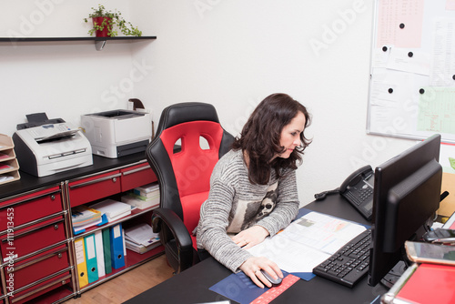 Receptionist woman at the doctor’s office reception desk working on computer 