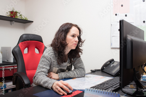 Receptionist woman at the doctor’s office reception desk working on computer 