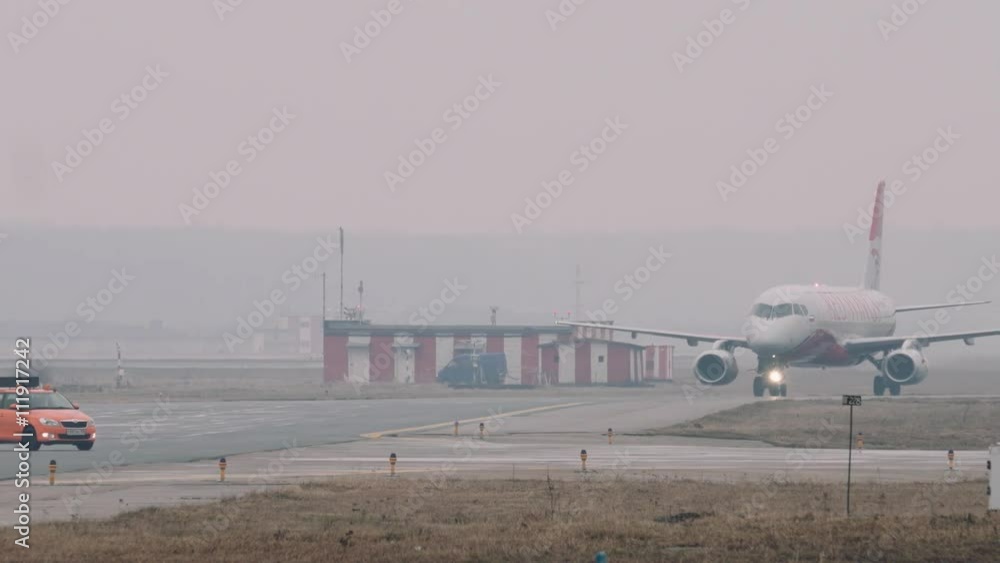 The Superjet 100 moving on a taxiway in the airport in a rainy day. Some airport facilities in the background, 2160p UHD 4k The Superjet 100 moving on a taxiway in the airport in a rainy day. Some airport facilities in the background, 2160p UHD 4k