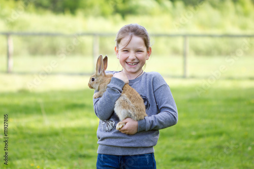 Cheerful little girl holding a real rabbit