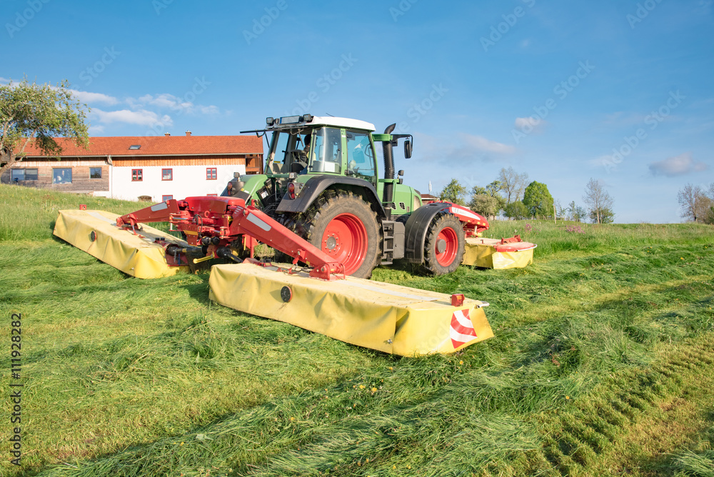 Fototapeta premium Landwirtschaft im Allgäu, Landwirt mäht Gras für Silage