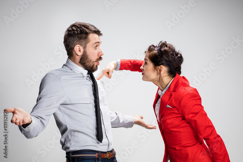 The angry business man and woman conflicting on a gray background