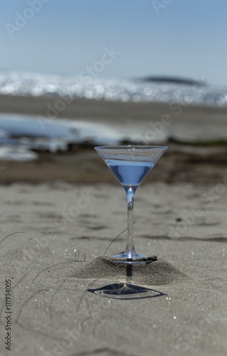 Glass with water on the sandy beach