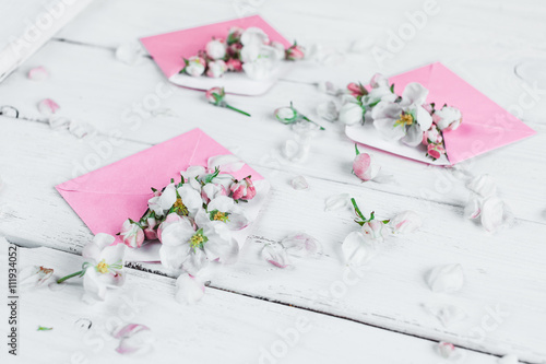 Fototapeta Naklejka Na Ścianę i Meble -  pink envelopes with flowers on white wooden background, closeup