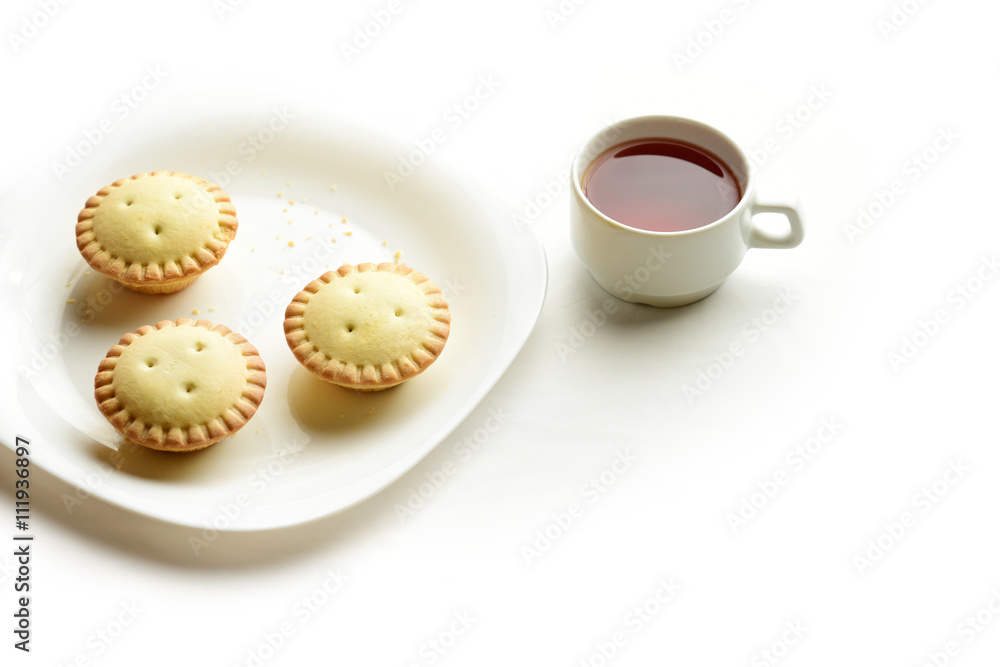 Shortcrust tartlets on a plate with a cup of black tea isolated on white background Shortcrust tartlets on a plate with a cup of black tea isolated on white background