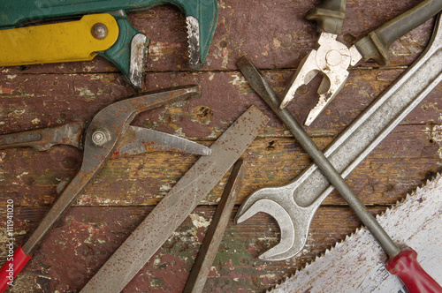 Heap of old instruments on wooden background. Wrench,file,screwdriver,pliers,scissors,saw.