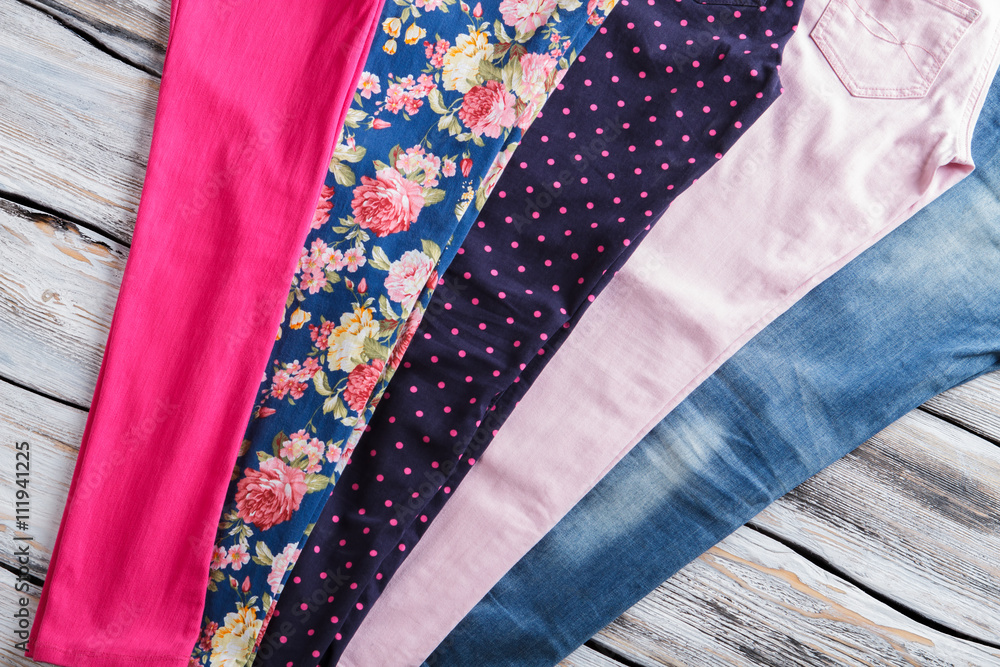 Light pink pants and jeans. Bright casual trousers for women. Garments on white wooden shelf. Selection of pants in boutique. Light pink pants and jeans. Bright casual trousers for women. Garments on white wooden shelf. Selection of pants in boutique.