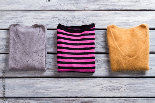 Pink and black striped pullover. Sweaters on gray wooden background. What to wear this autumn. Only high quality goods.