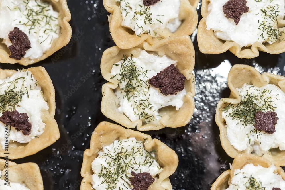 Flower tarts with cheese and spices on a black background