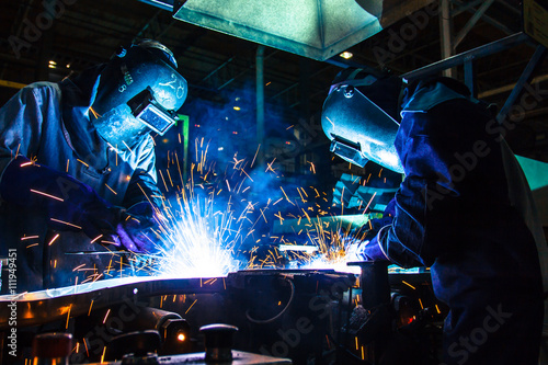 Teamworker with protective mask welding metal