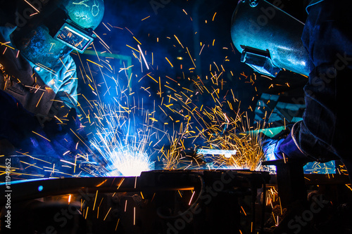 Teamworker with protective mask welding metal