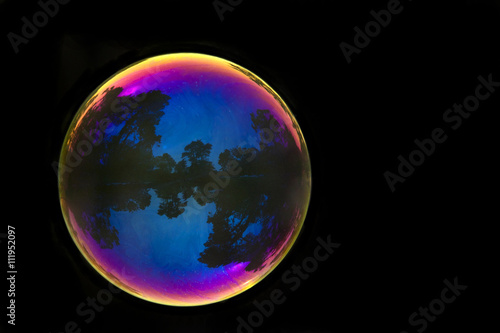 Large soap bubble reflecting outdoor park scene from San Francisco Golden Gate Park isolated on dark background