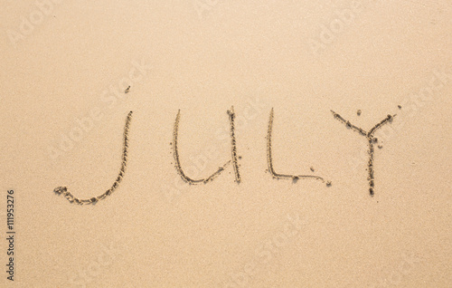 July - written in sand on beach texture  months year series