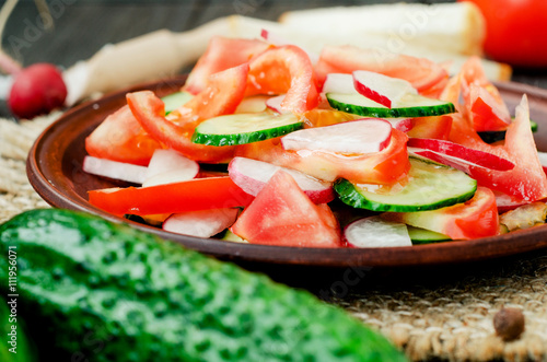  healthy salad with fresh ripe summer vegetables , tomato, cucumber , radishes , spices and white toast on a wooden background