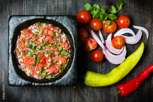 Photography Tomato sauce salsa and ingredients dark stone background.