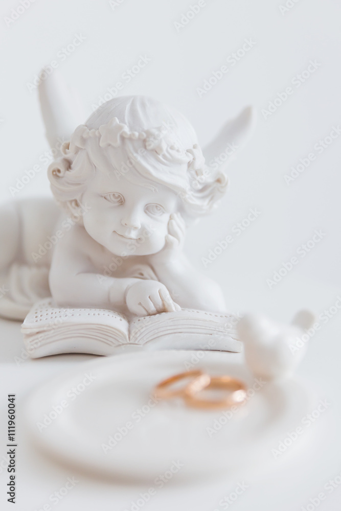 Pair of golden wedding rings with white figures of bird and angel. Symbol of love and marriage. Pair of golden wedding rings with white figures of bird and angel. Symbol of love and marriage.