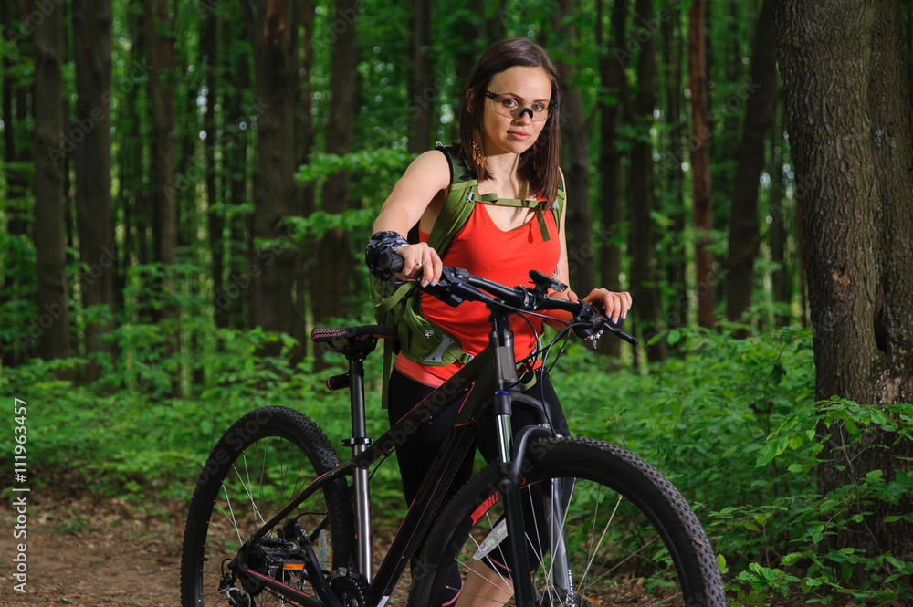 Naklejka premium Girl riding a bike in the woods