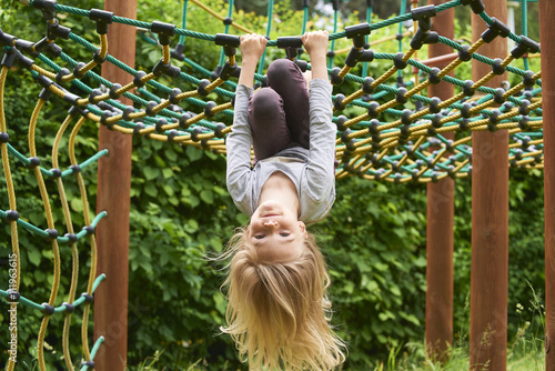 Portrait of Happy little blond girl playing on a rope web playground outdoor photo