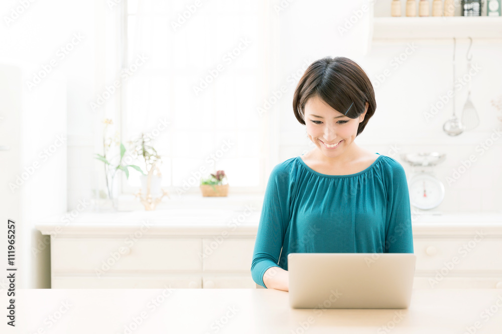 young asian woman using laptop in the kitchen young asian woman using laptop in the kitchen